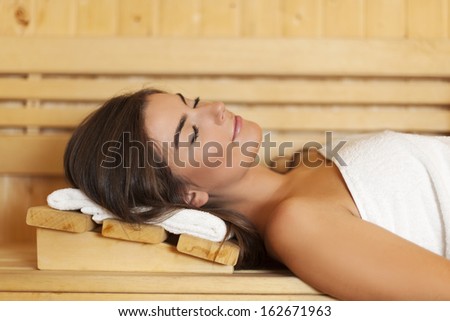 Woman wrapped in white towel laying in sauna