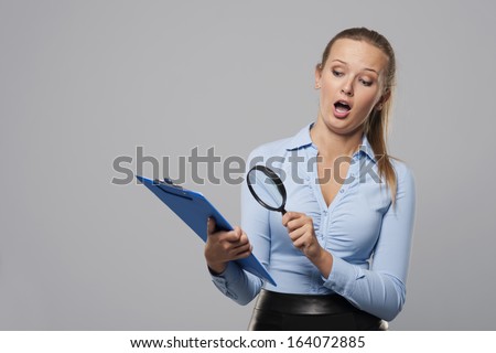 Shocked woman looking at office documents with magnifier