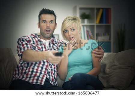 Scared couple watching horror movie
