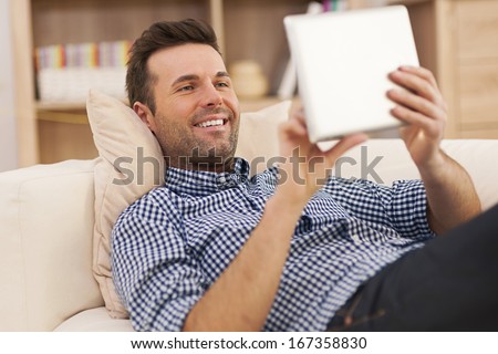 Happy man relaxing on sofa with digital tablet