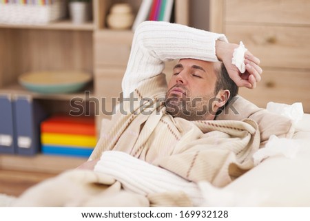 Sick Man Lying Down On Couch With High Fever