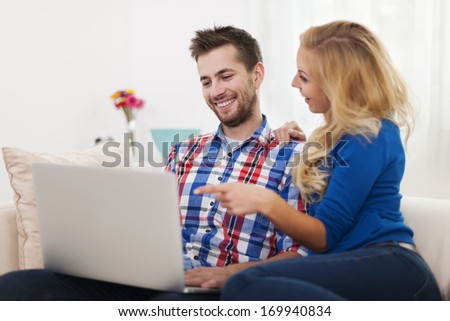 Happy couple using computer at home
