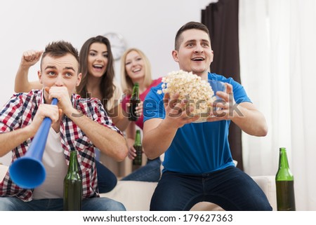 Young group of people celebrating win of favourite sports team