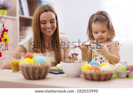 Focus little girl painting easter eggs with her mother