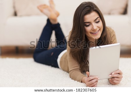 Happy woman on carpet using digital tablet