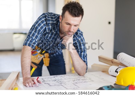 Building contractor bending over home plans