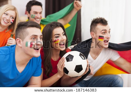 Multinational friends cheering football match at home
