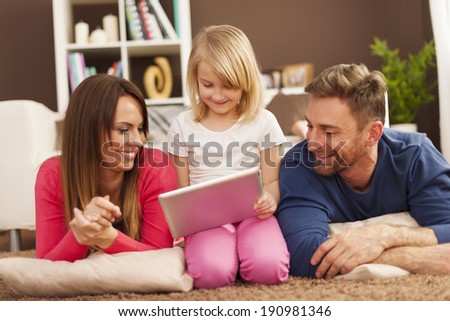 Loving family using digital tablet on carpet