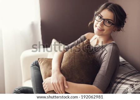 Woman wearing fashion glasses sitting on sofa at home