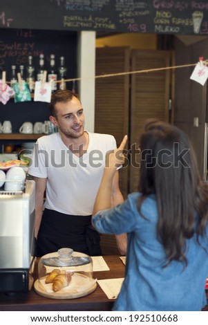 Smiling male waiter receives order from young woman