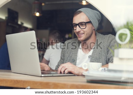 Handsome hipster using laptop at cafe Handsome hipster using laptop at cafe