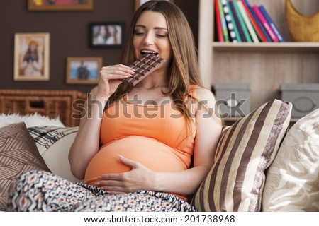 Pregnant woman enjoying of eating chocolate
