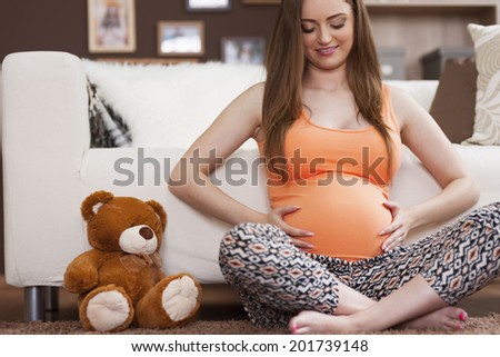 Pregnant woman with lovely teddy bear at home