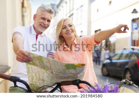 Mature couple riding a bike with map in the city
