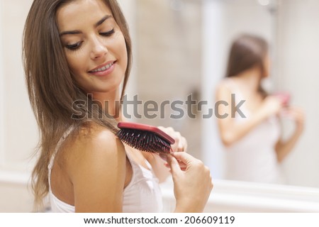 Gorgeous brunette woman brushing her healthy hair