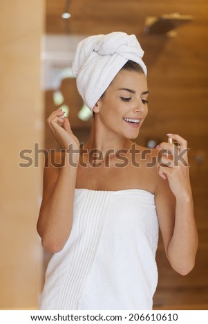Beauty woman wrapped in towel applying perfume
