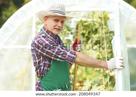 Mature man in front of greenhouse