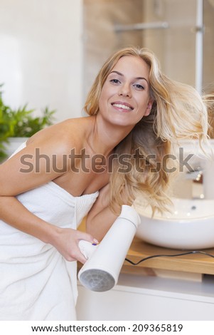 Blonde woman drying hair after the shower