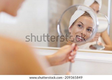 Beautiful woman looking herself reflection in small mirror