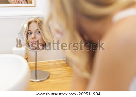Woman caring about her skin on face in front of small mirror