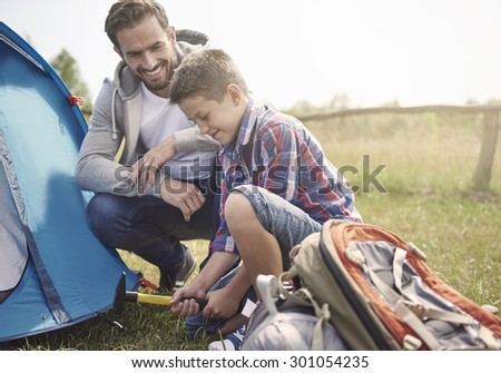 Father teaching son how to pitch a tent