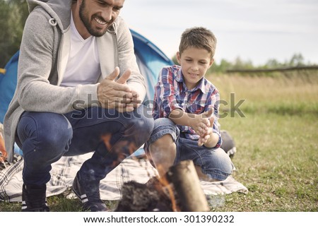 Father and son rubbing hands over the campfire