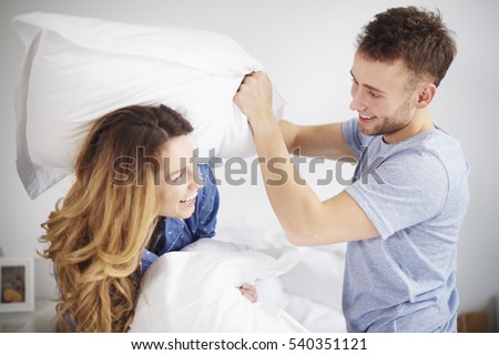 Couple having pillow fight in bedroom