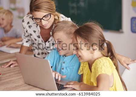 Teacher with students using laptop in classroom