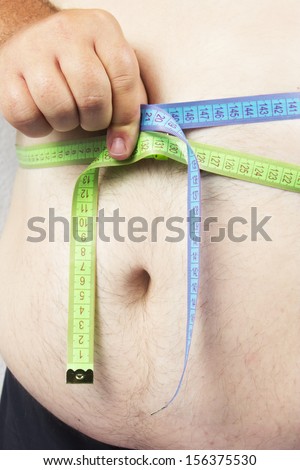 Fat man holding a measurement tape against white background