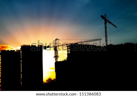 Cranes and building construction site against blue sunset sky