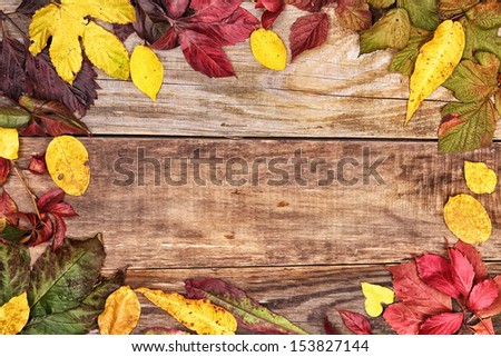 Frame of autumn leaves on old wood background