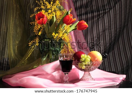 Still life with tulips, mimosa flowers and wine with fruits