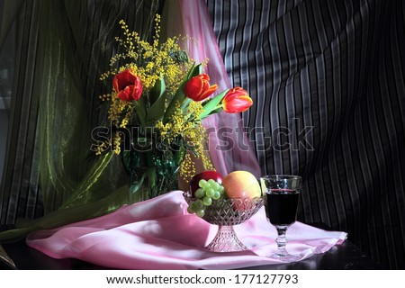 Still life with tulips, mimosa flowers and glass of red wine with fruits