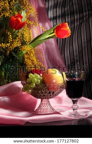 Still life with tulips, mimosa flowers and red wine with fruits