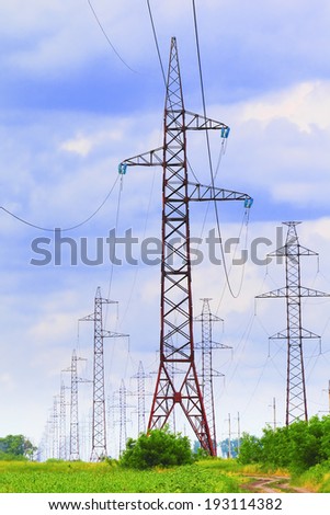 Row of pylons and transmission power lines on the dramatic blue sky background