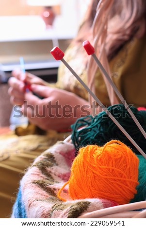 Close-up of basket with balls of yarn  and woman knitting