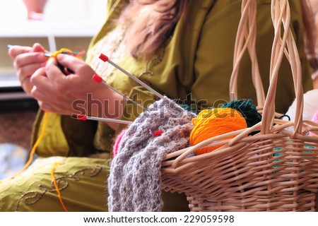 Close-up of basket with balls of yarn  and woman knitting
