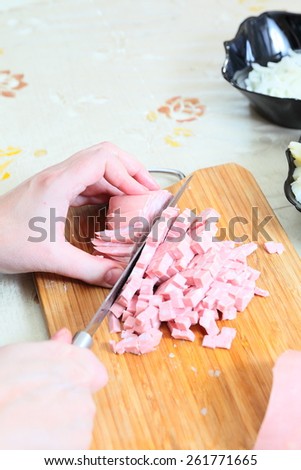 Preparing russian traditional salad Olivier, chopping sausage