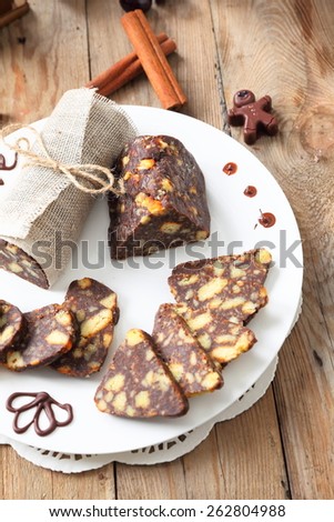 sliced chocolate sausage with various decorations on a wooden table