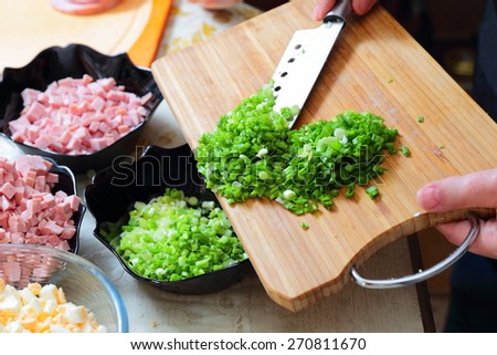Preparing russian traditional salad Olivier, chopping green onion