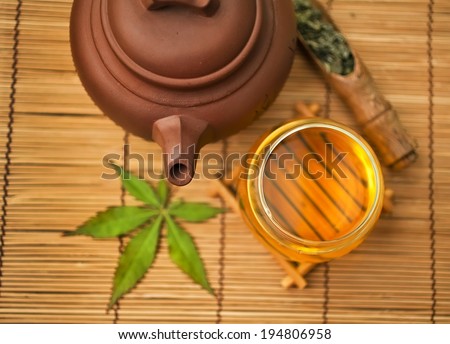 Chinese clay teapot with glass bowl of green tea and japanese maple leaf and bamboo tea scoop