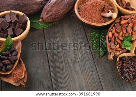 Cacao beans and powder, cacao butter and cacao nibs and chocolate on a wooden background