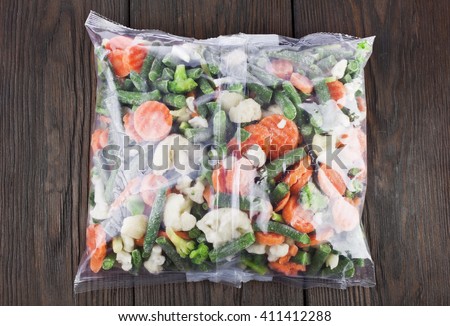 Packet of frozen vegetables on a old wooden table, top view