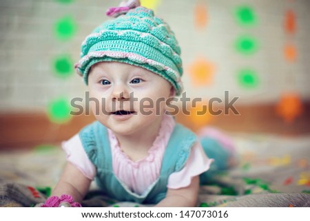 baby in knitted cap on his head, lying on the carpet