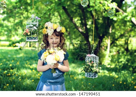 girl standing in the park, on a head a wreath of flowers, in his hands holding a bouquet of flowers. smiles