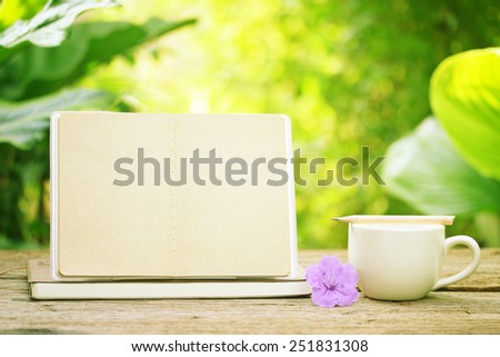 Notebook and white coffee cup with purple flower at outdoor