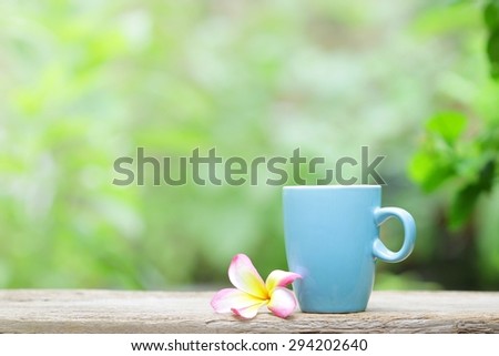 blue mug and plumaria flower on wood table