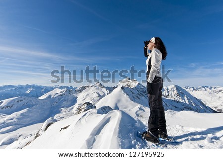 View from the top: a girl looking over the horizon from the top of a mountain, after a hike with snowshoes in winter