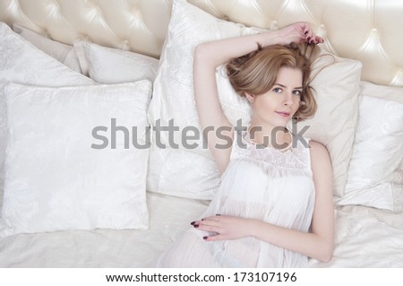 Sexy blonde woman in a white nightgown laying on the bed