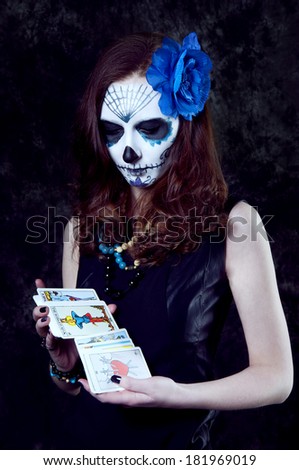 Woman witch with scary makeup with tarot cards preparing for a reading